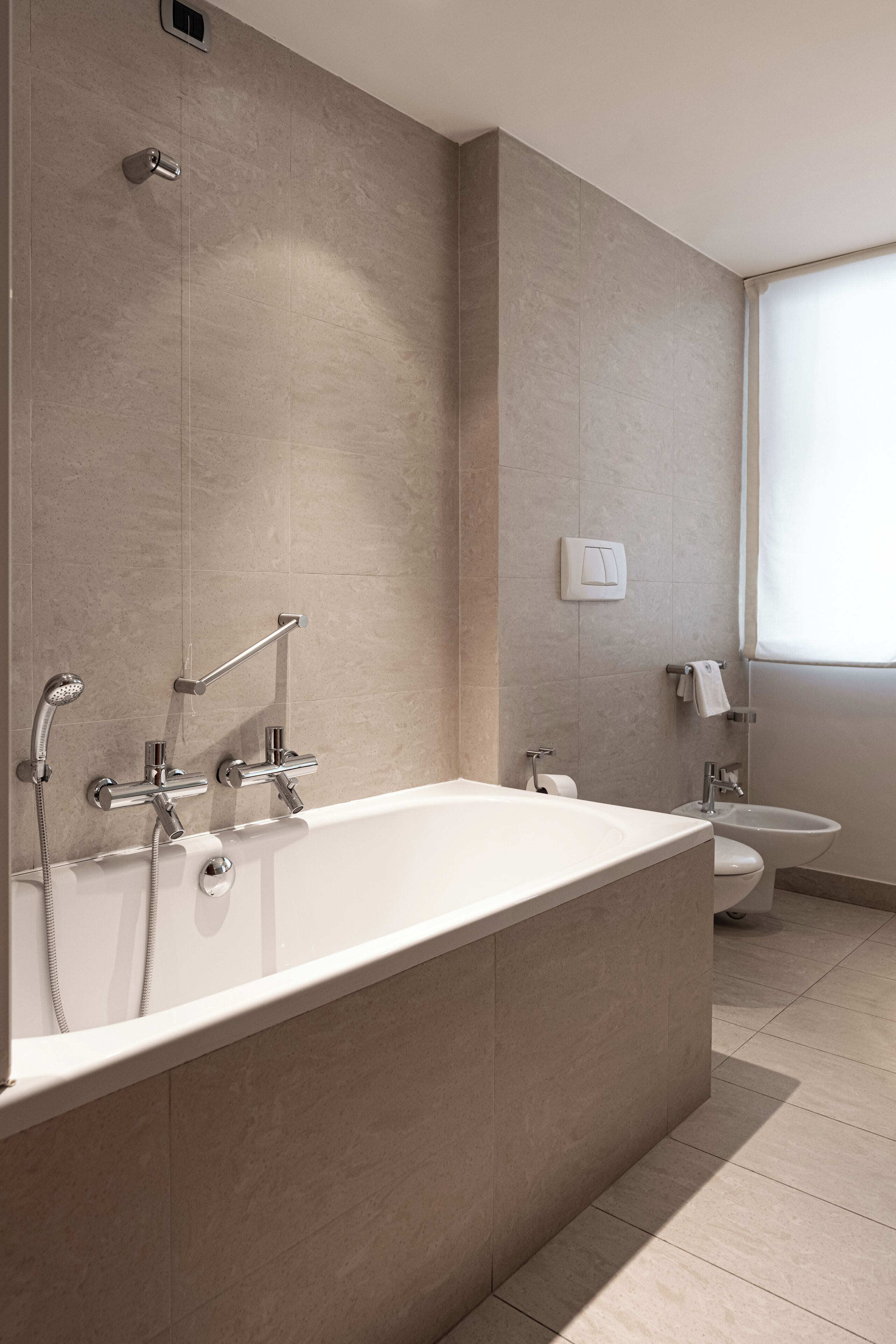 Une salle de bain moderne dotée d’une grande baignoire, de toilettes séparées et d’un bidet.