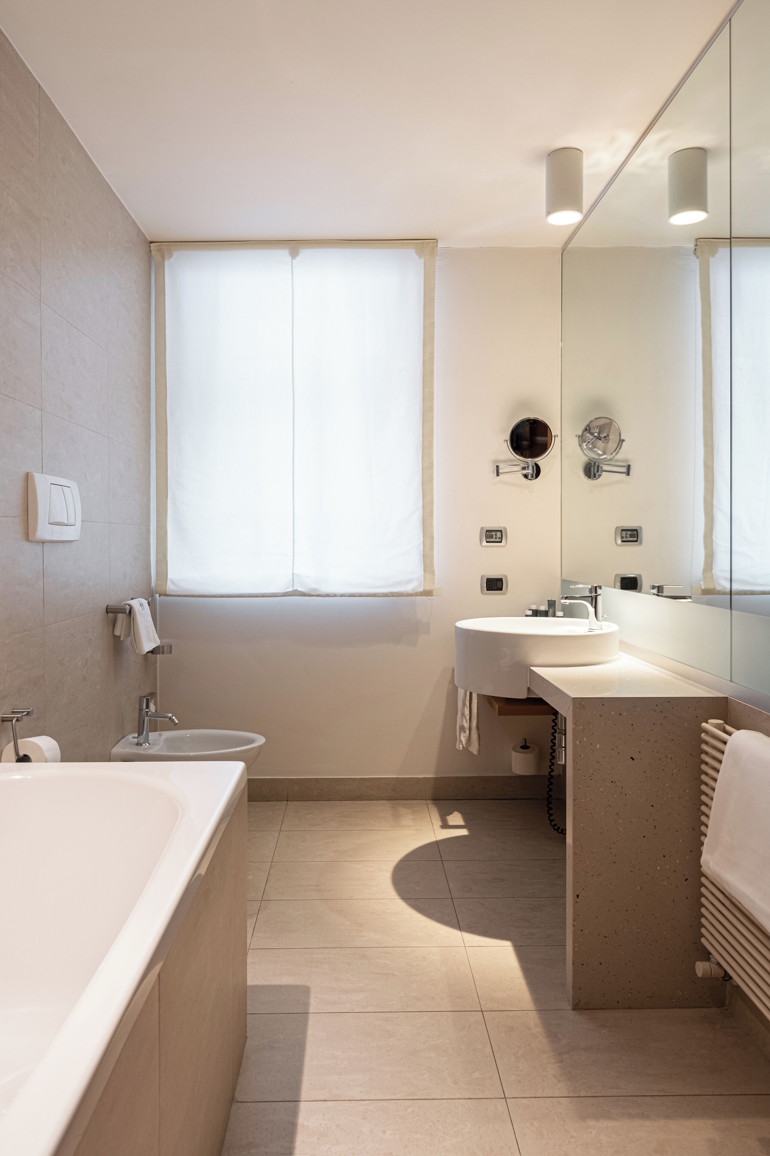 A modern bathroom with a bathtub, sink, and mirror.