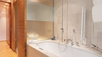 Um banheiro moderno com uma banheira grande, box de vidro e painel de parede de madeira.