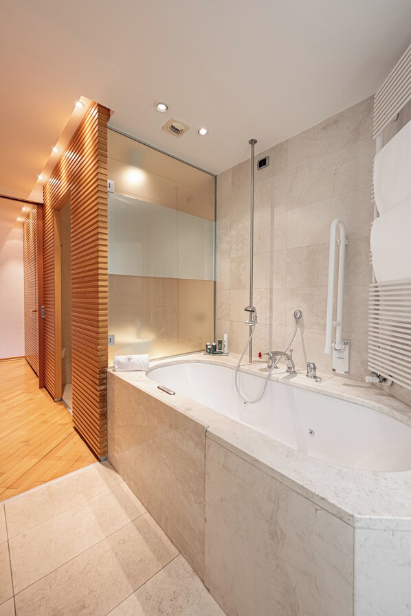 Une salle de bain moderne avec une grande baignoire, une cabine de douche en verre et un mur recouvert de panneaux en bois.