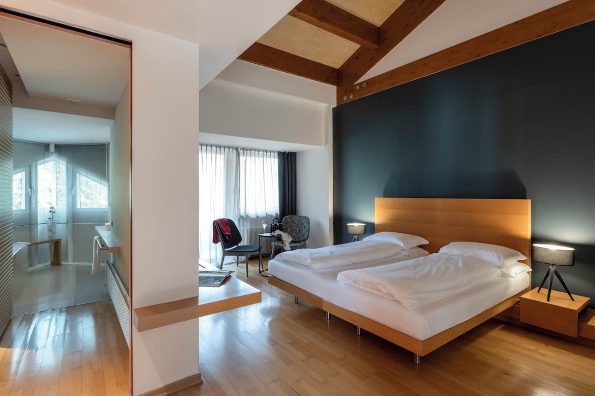A modern hotel room with a large bed, a desk, and a chair.
