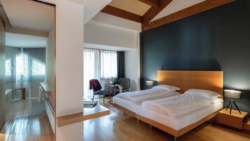 Ein modernes Hotelzimmer mit einem großen Bett, Nachttischen, einem Schreibtisch und einem Sessel.