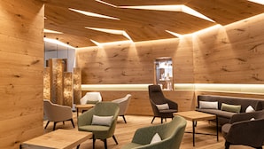 A modern interior with wooden walls and ceiling, featuring a seating area with multiple chairs and a sofa. - Grand Hotel Terme di Comano (Stenico)