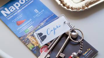 A brochure titled "Napoli" with a keychain and a pastry on a table.