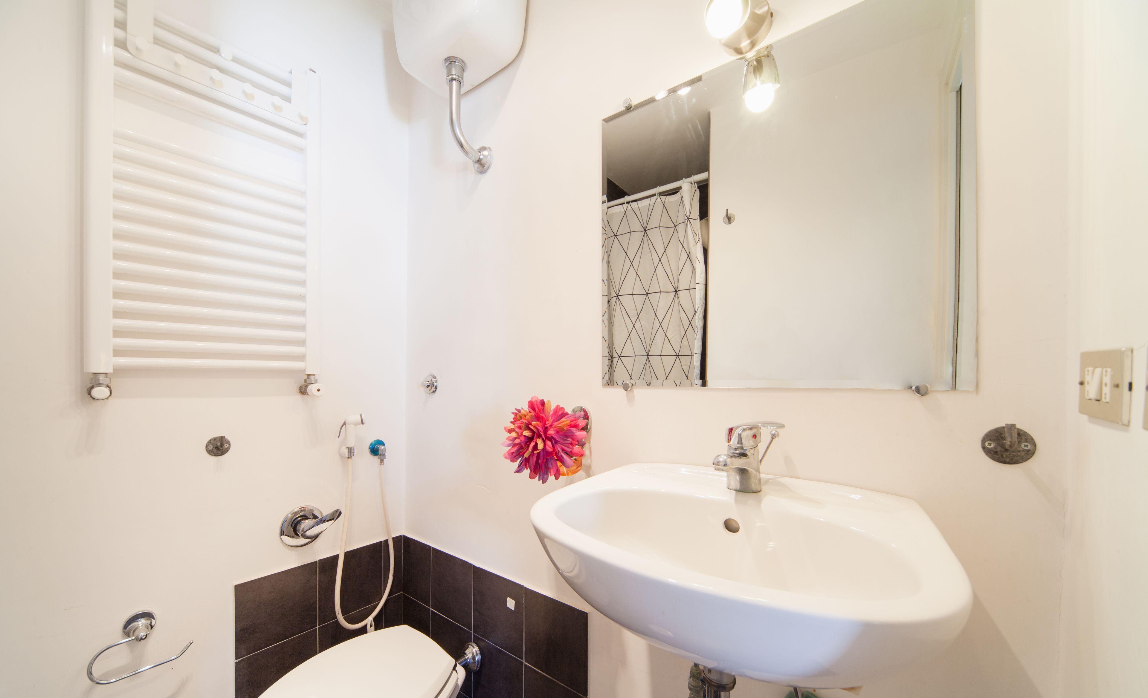 A bathroom with a white sink, a mirror, a shower, and a toilet.