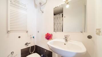 A bathroom with a white sink, a mirror, a shower, and a toilet.