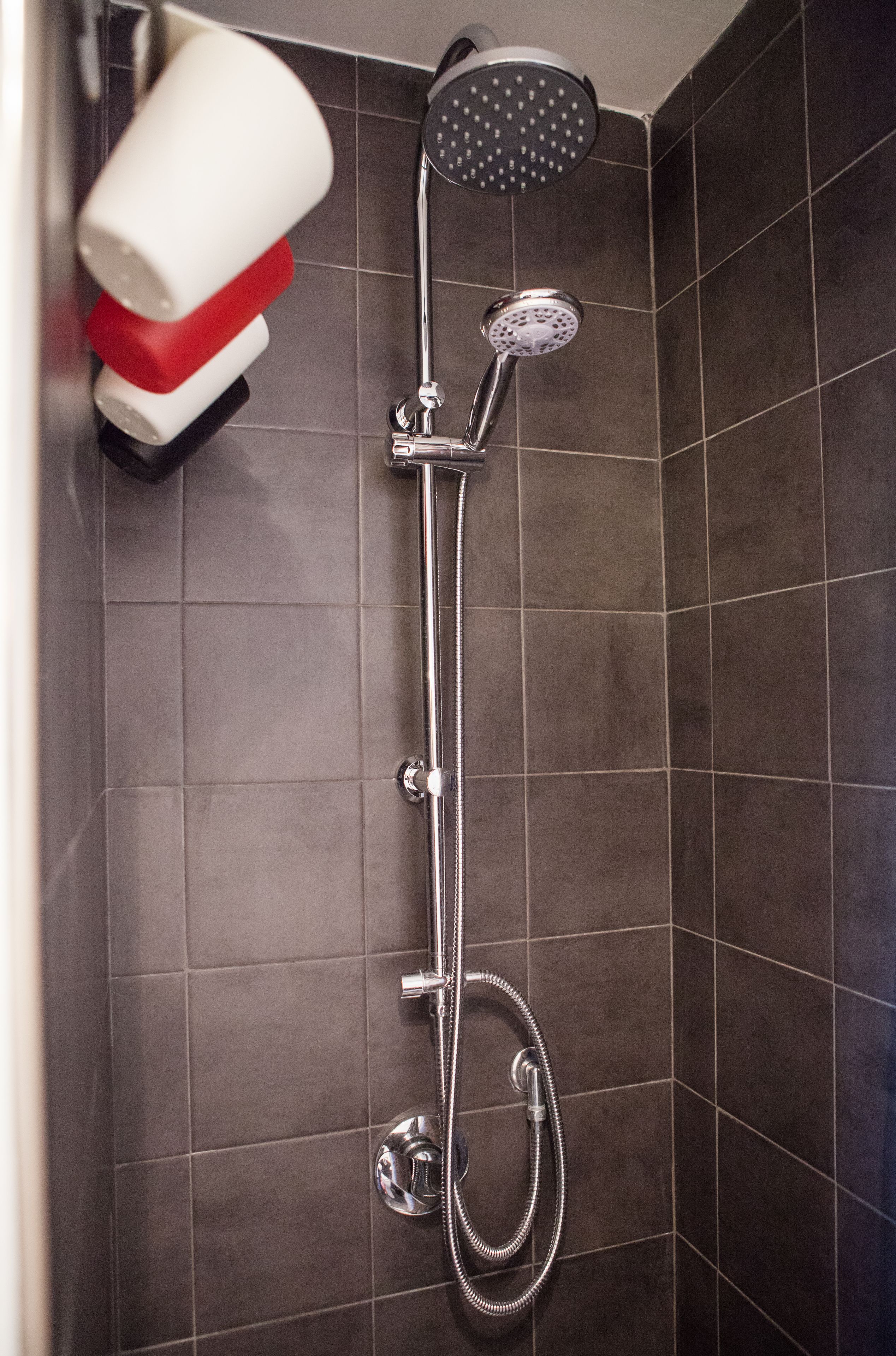 Una ducha con cabezal de ducha de mano y cabezal de ducha tipo lluvia instalado en la pared.