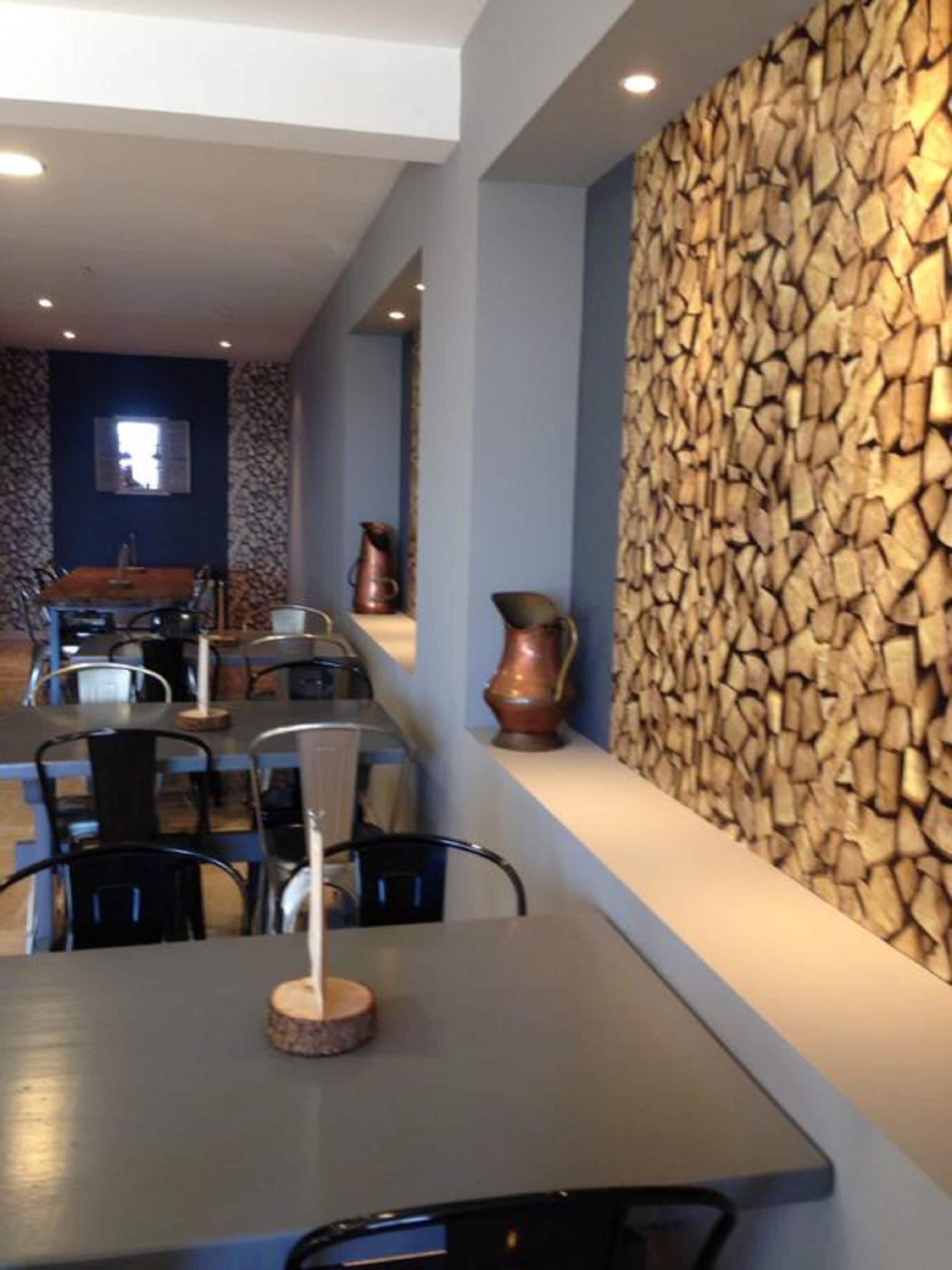 Un comedor moderno con pared de piedra y sillas de metal.