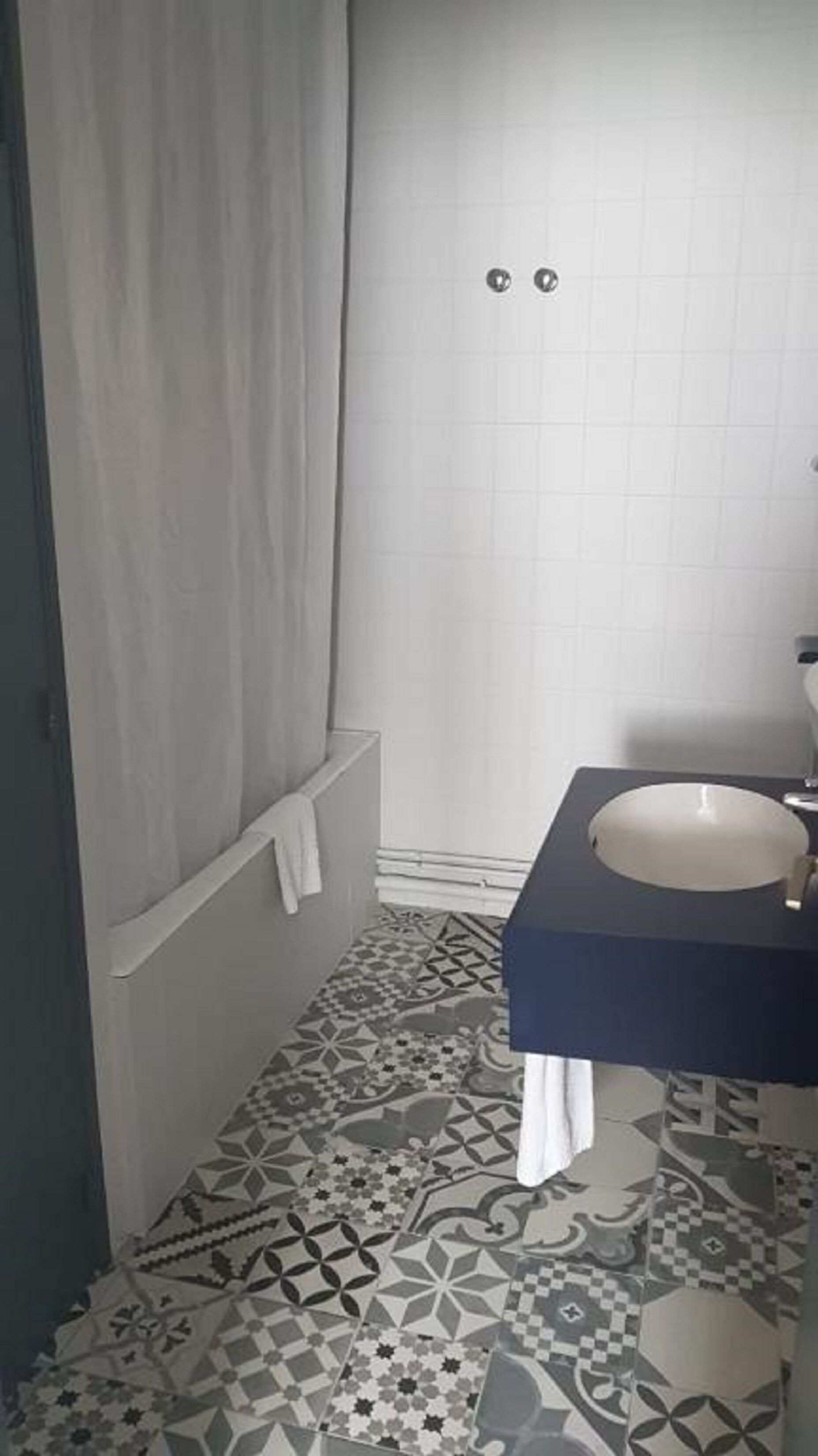 Une salle de bain avec un carrelage décoratif, une baignoire, un lavabo et un espace douche.