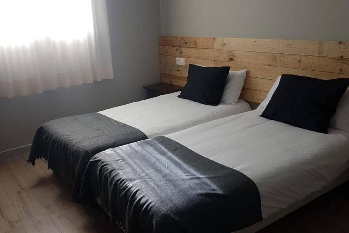 Una cama doble con cabecera de madera, una mesita de noche y una silla.