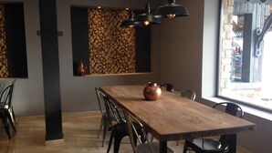 Een eetgedeelte met een houten tafel, zwarte stoelen en hanglampen.
