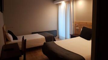 A hotel room with two beds, a desk, and a chair.