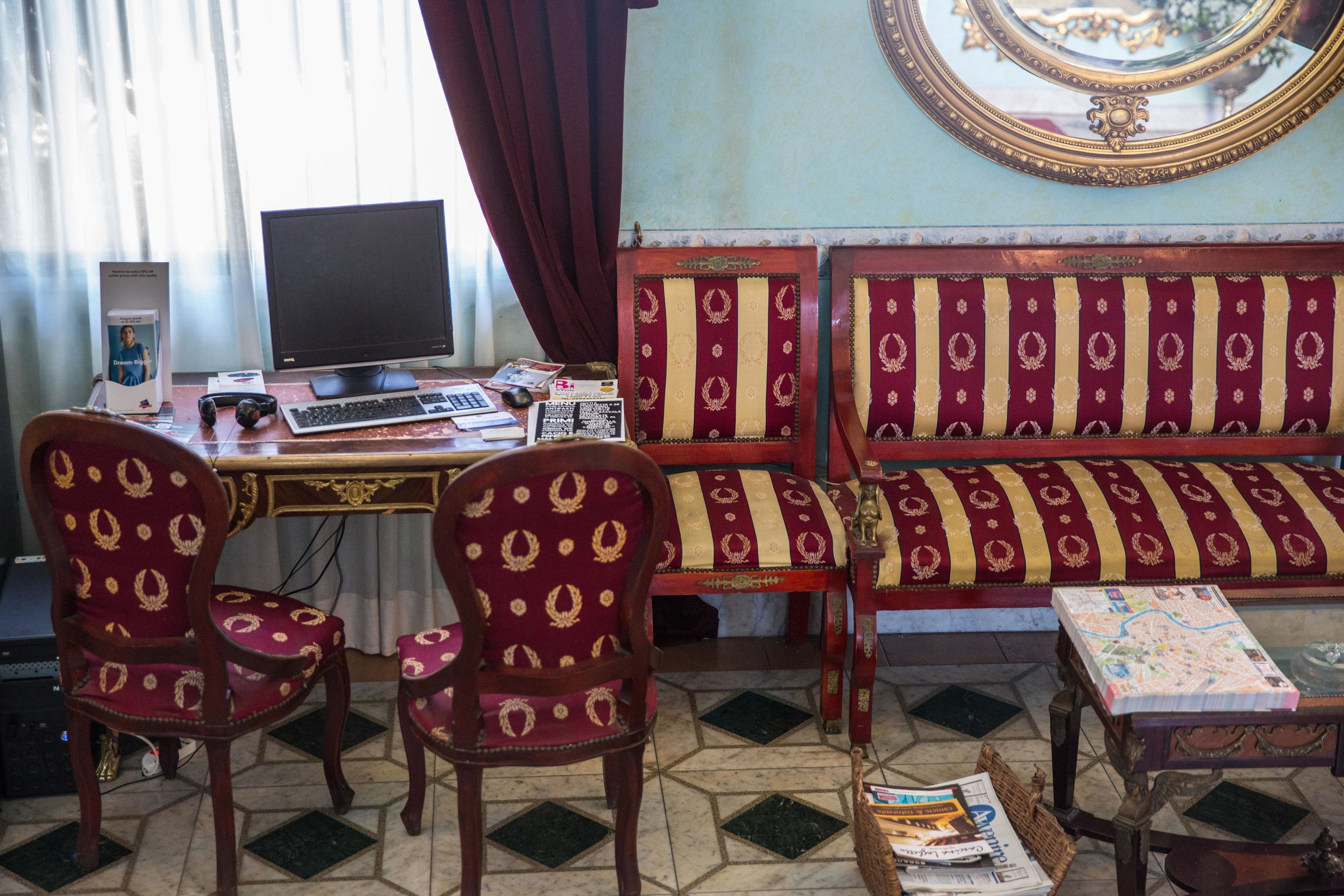 A room with a desk, two chairs, a sofa, a computer, and a map on a table.