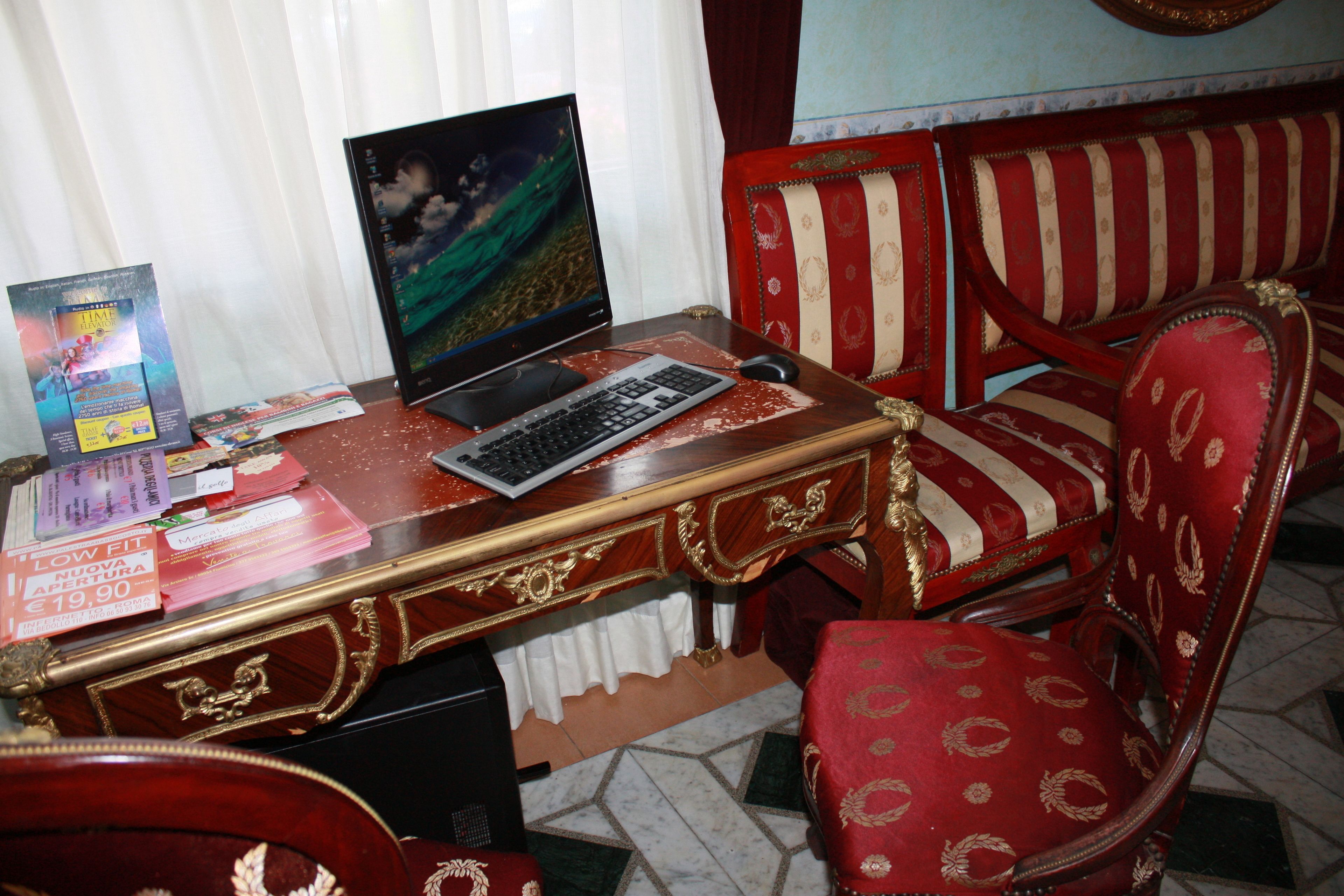 A room with a wooden desk, a computer, and a red upholstered chair.