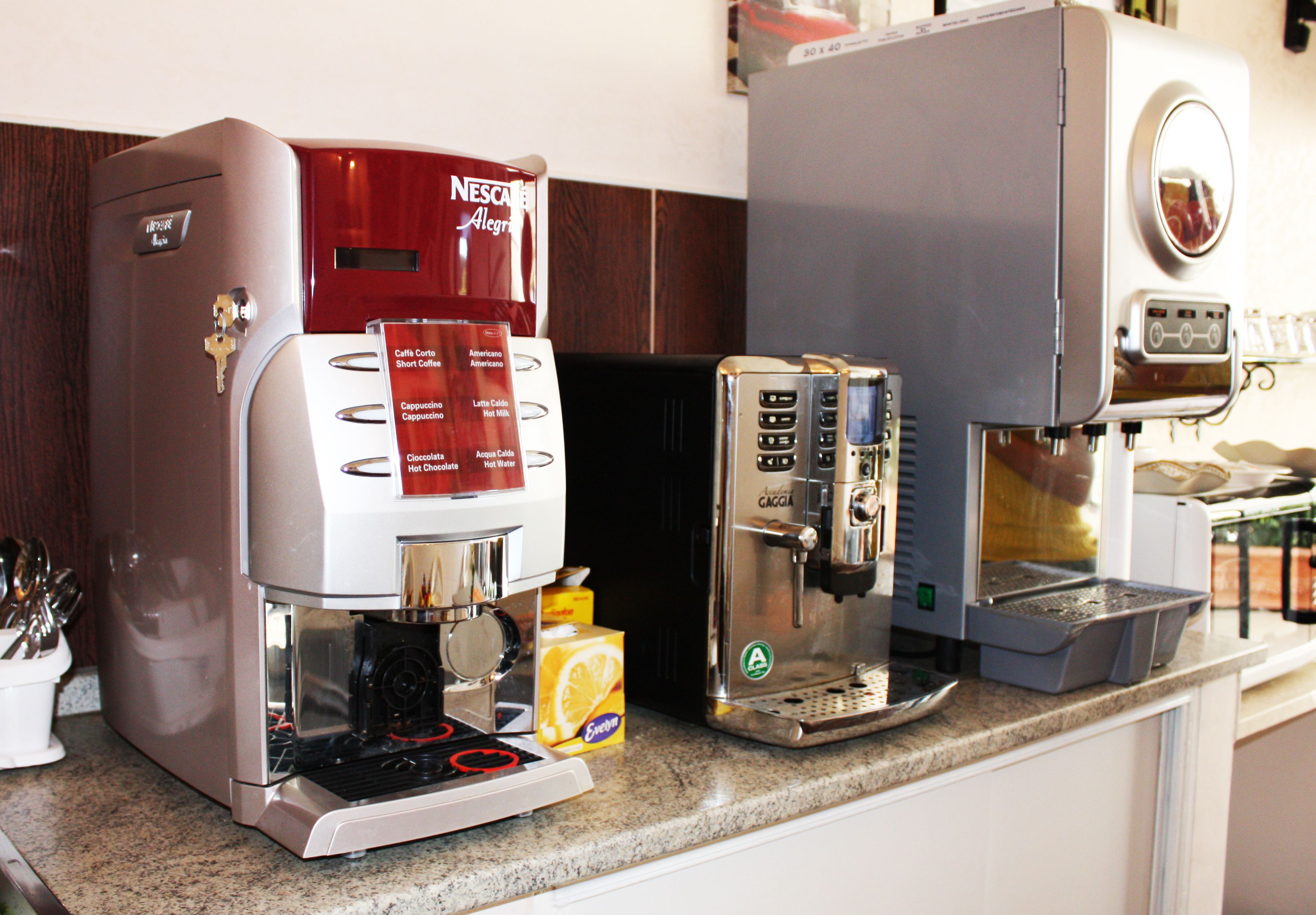 Máquina de café com várias opções, moedor de café e cafeteira em uma bancada de cozinha.