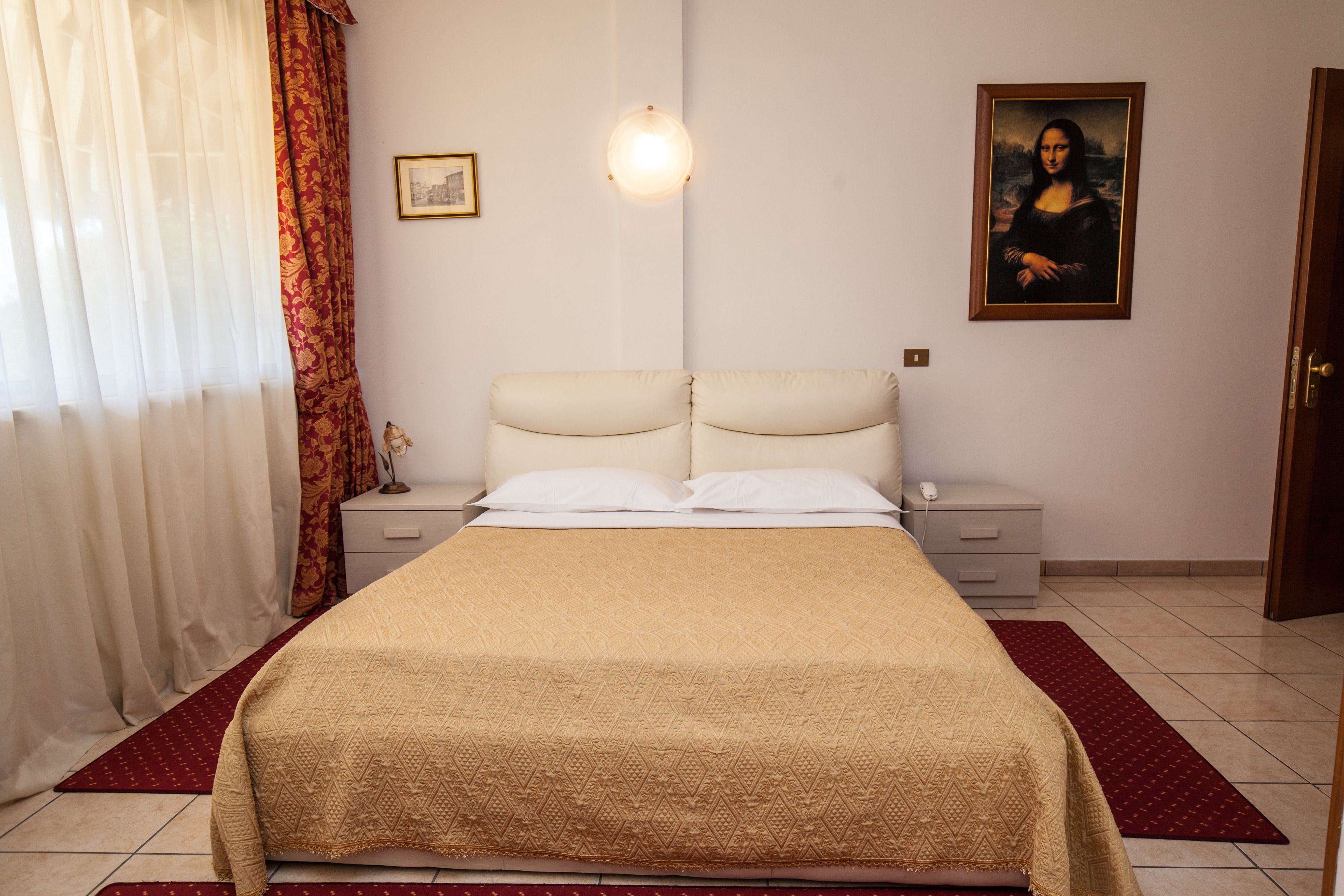A bedroom with a bed, nightstands, a lamp, a painting, and a door.