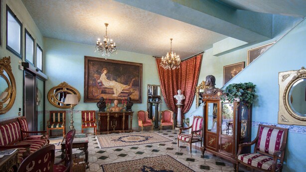 Una habitación amplia con un cuadro grande, muebles ornamentados y un candelabro.