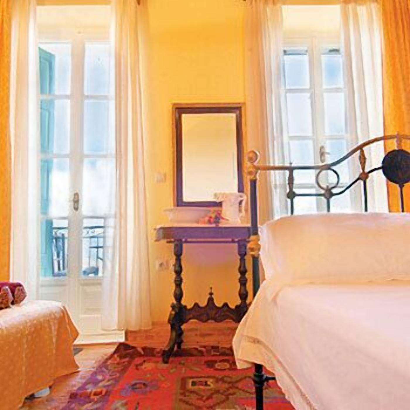 A bedroom with a bed, a bedside table, a mirror, and a view of the outside through a door.