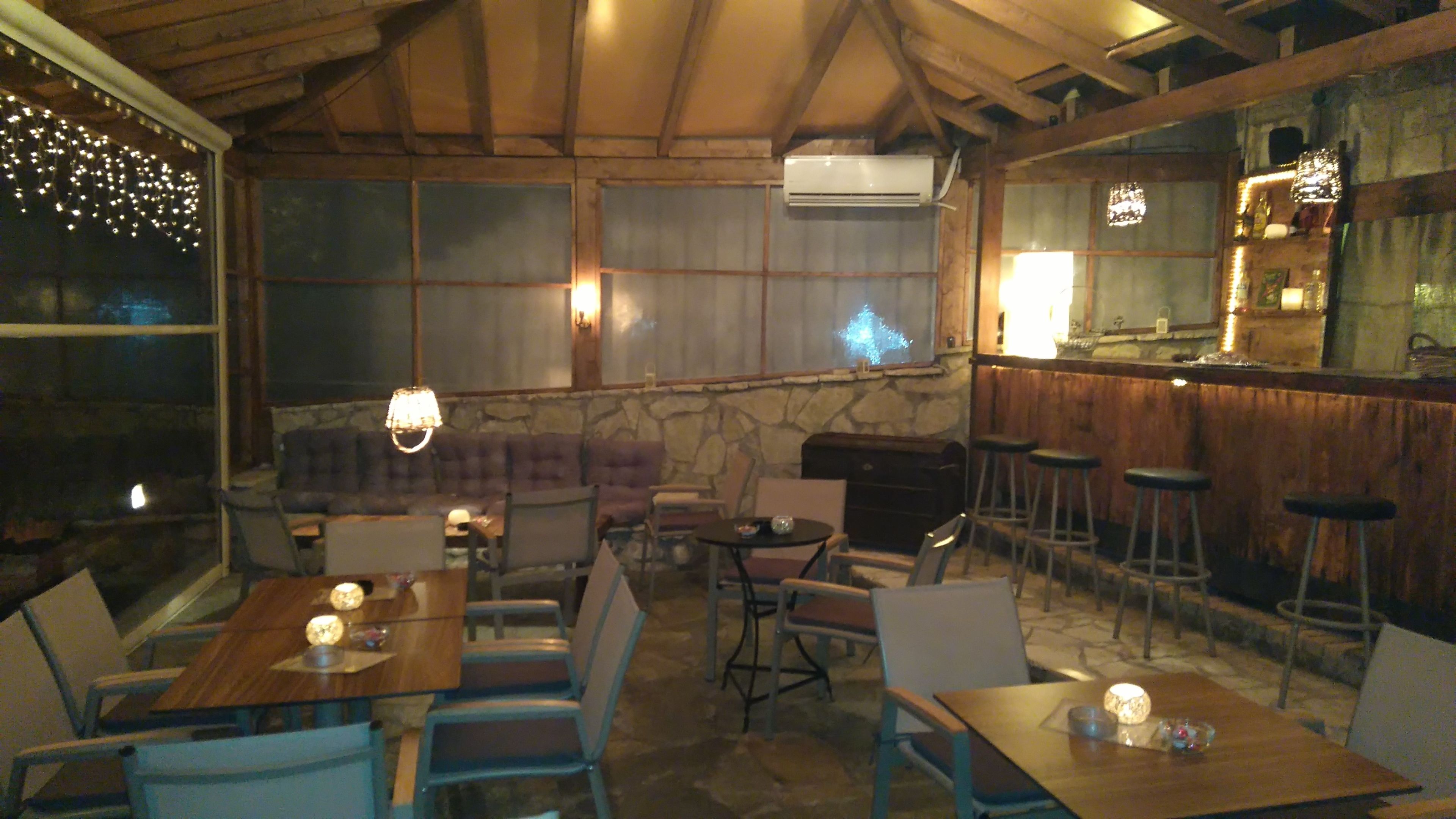 Un espace de restauration intérieur avec des tables et des chaises en bois, des murs en pierre et un bar équipé de tabourets.