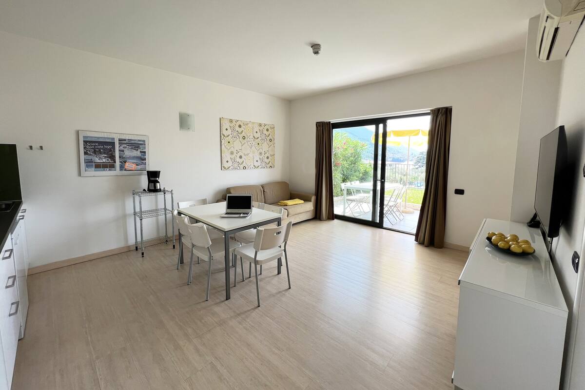 Una sala de estar moderna con comedor, sofá, máquina de café y televisor.