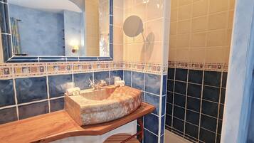 A bathroom with a marble sink, a mirror, and a towel rack.
