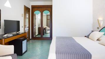 A hotel room with a bed, a TV, a desk, and a mirror.
