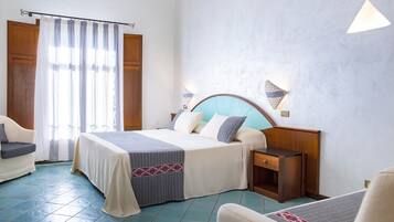 Une chambre d’hôtel avec un lit, des tables de chevet, une chaise, un bureau et une fenêtre avec des rideaux.