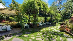 An outdoor garden with stone pathways, tables, and chairs arranged for dining. - Hotel Des Reves - Al Poggio di Casalucense (Sant'Elia Fiumerapido)
