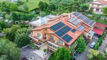 Een meerlaags huis met zonnepanelen op het dak, een binnentuin met een fontein en een weelderige groene tuin.