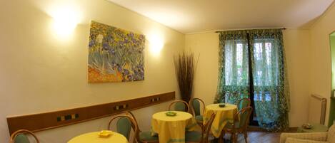 A dining area with round tables, chairs, and a painting on the wall.
