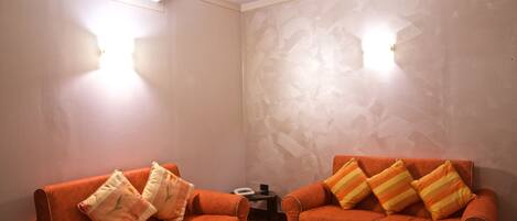 A room with two orange sofas, each with striped pillows, and a small table in the center.
