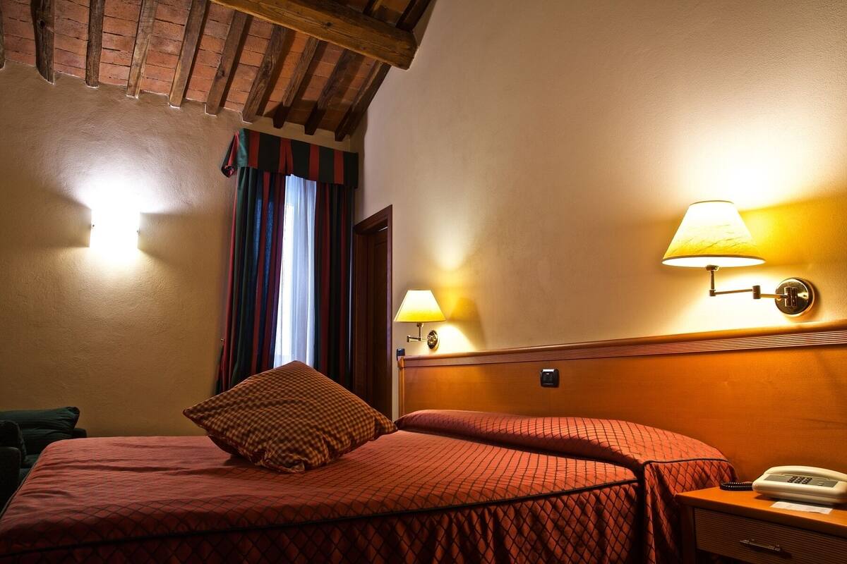 Une chambre d’hôtel avec un lit, deux lampes de chevet, un téléphone et une tête de lit en bois.