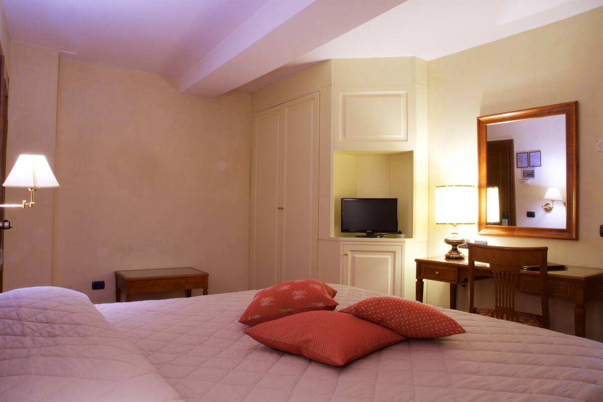 Une chambre d’hôtel avec un lit, une télévision, un bureau et une chaise.