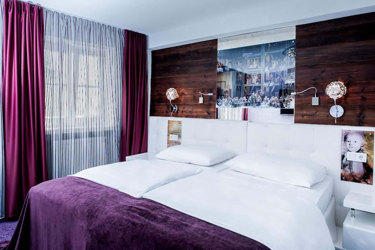 Habitación de hotel moderna con una cama grande, panel de pared de madera y vista a un espacio público.