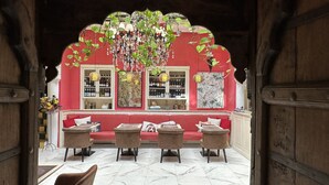 Un coin salon accueillant avec un mur rouge, un lustre et une bibliothèque.