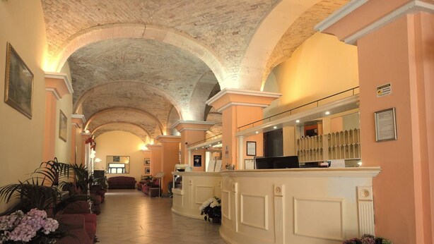 A hotel lobby with a high arched ceiling, a reception desk, and seating areas. - Hotel 4 Mori (Cagliari)