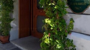 A hotel entrance with a sign reading "HOTEL 4 MORI" and a phone number. There are potted plants on either side of the entrance. - Hotel 4 Mori (Cagliari)