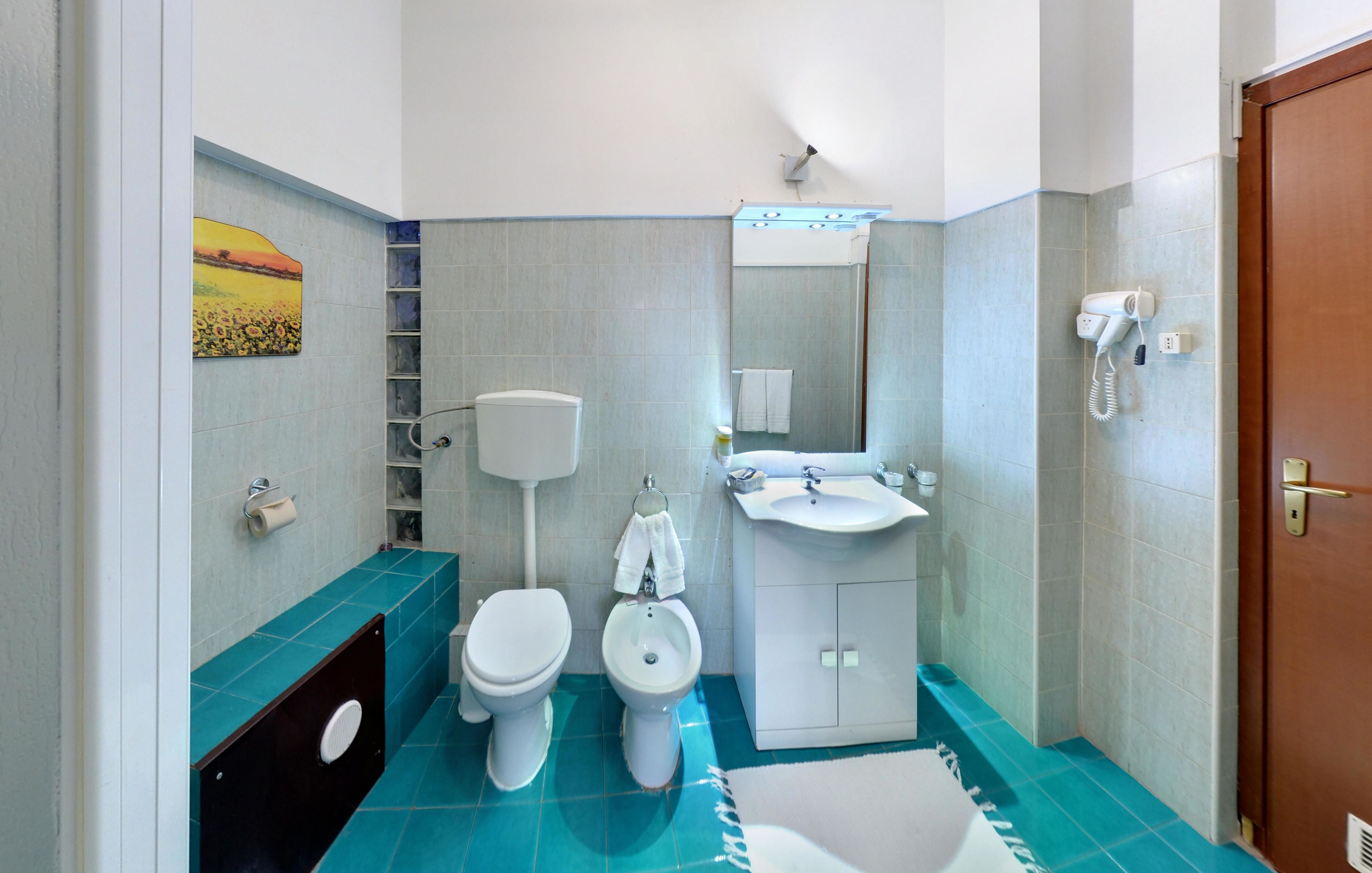 Une salle de bain équipée de toilettes, d’un bidet, d’un lavabo et d’un miroir.