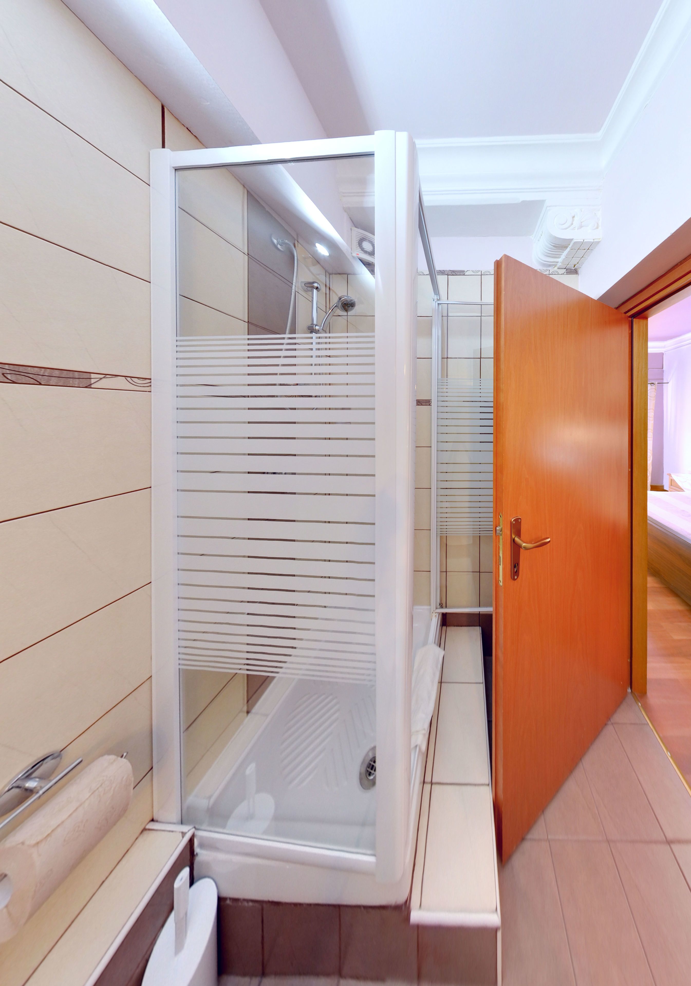 Ein modernes Badezimmer mit einer gläsernen Duschkabine, Holzwandverkleidung und einer Holztür.