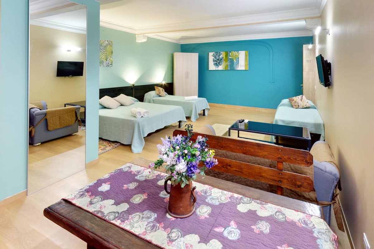 A hotel room with two beds, a sofa, a small table, and a decorative vase.