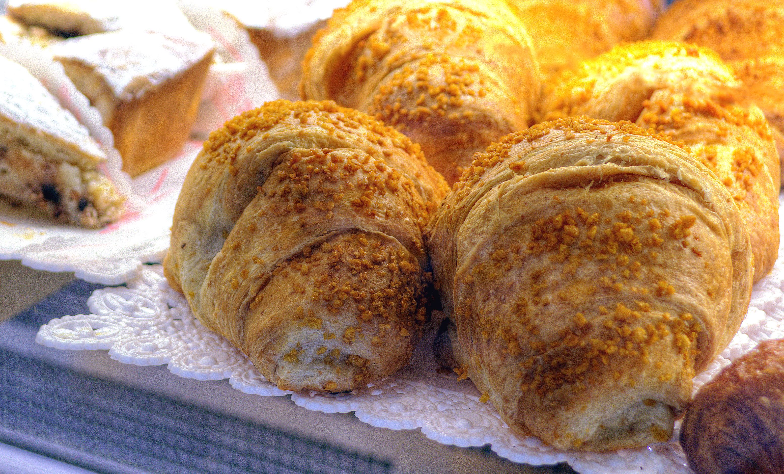 A display of pastries, including croissants and a slice of cake, on a white lace doily.