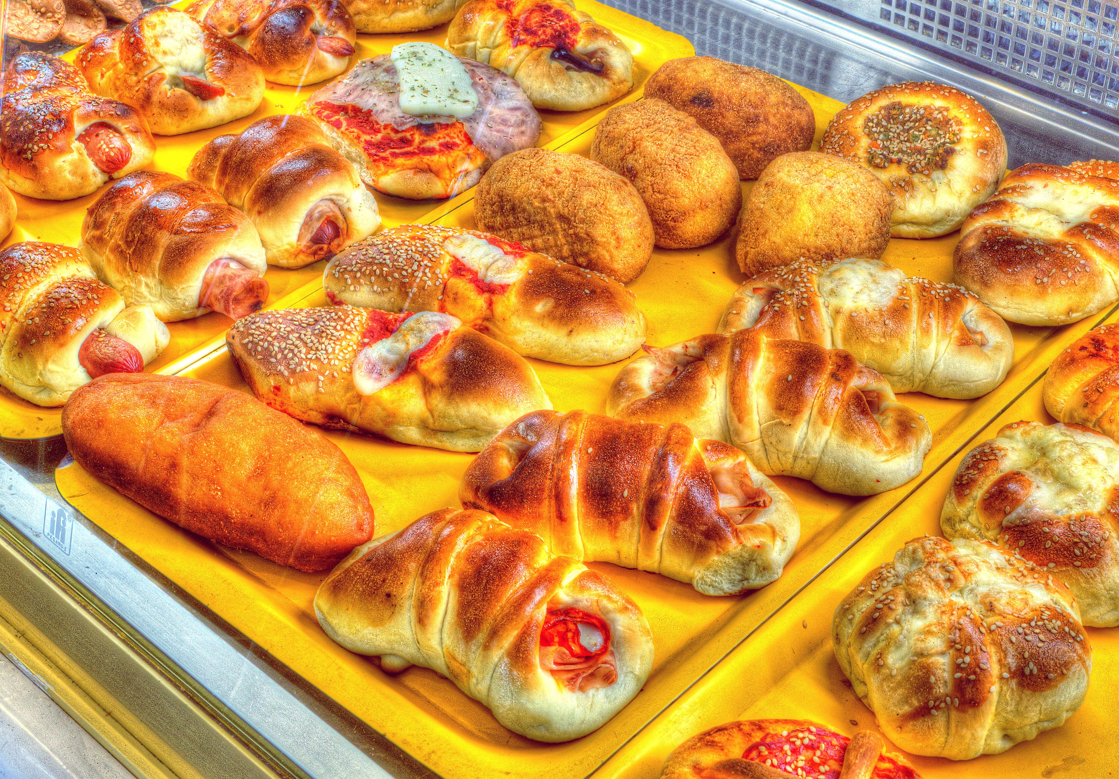 Una bandeja amarilla muestra una variedad de productos horneados, incluyendo bollos de pan y pasteles.