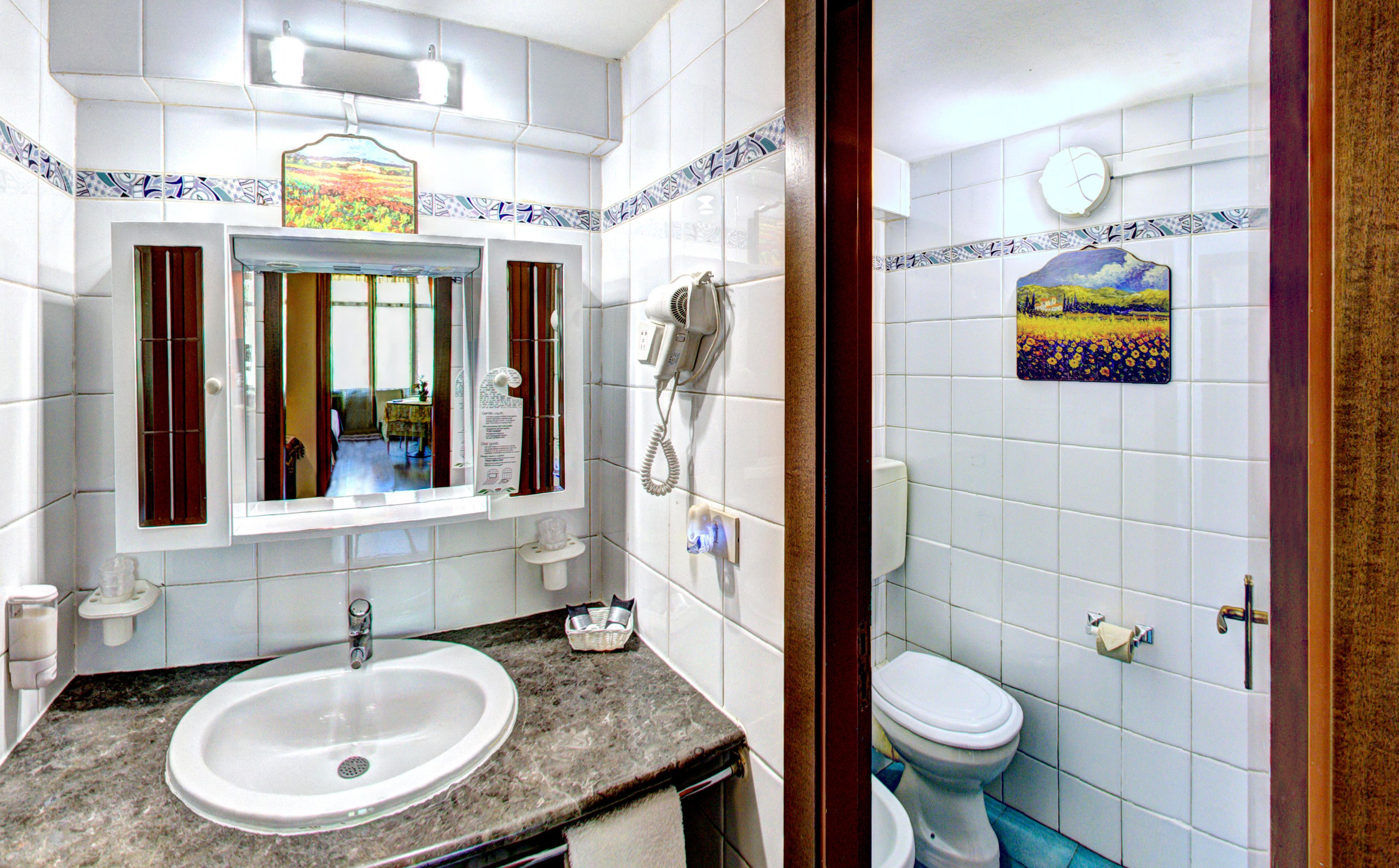 Un baño con lavabo, espejo e inodoro.