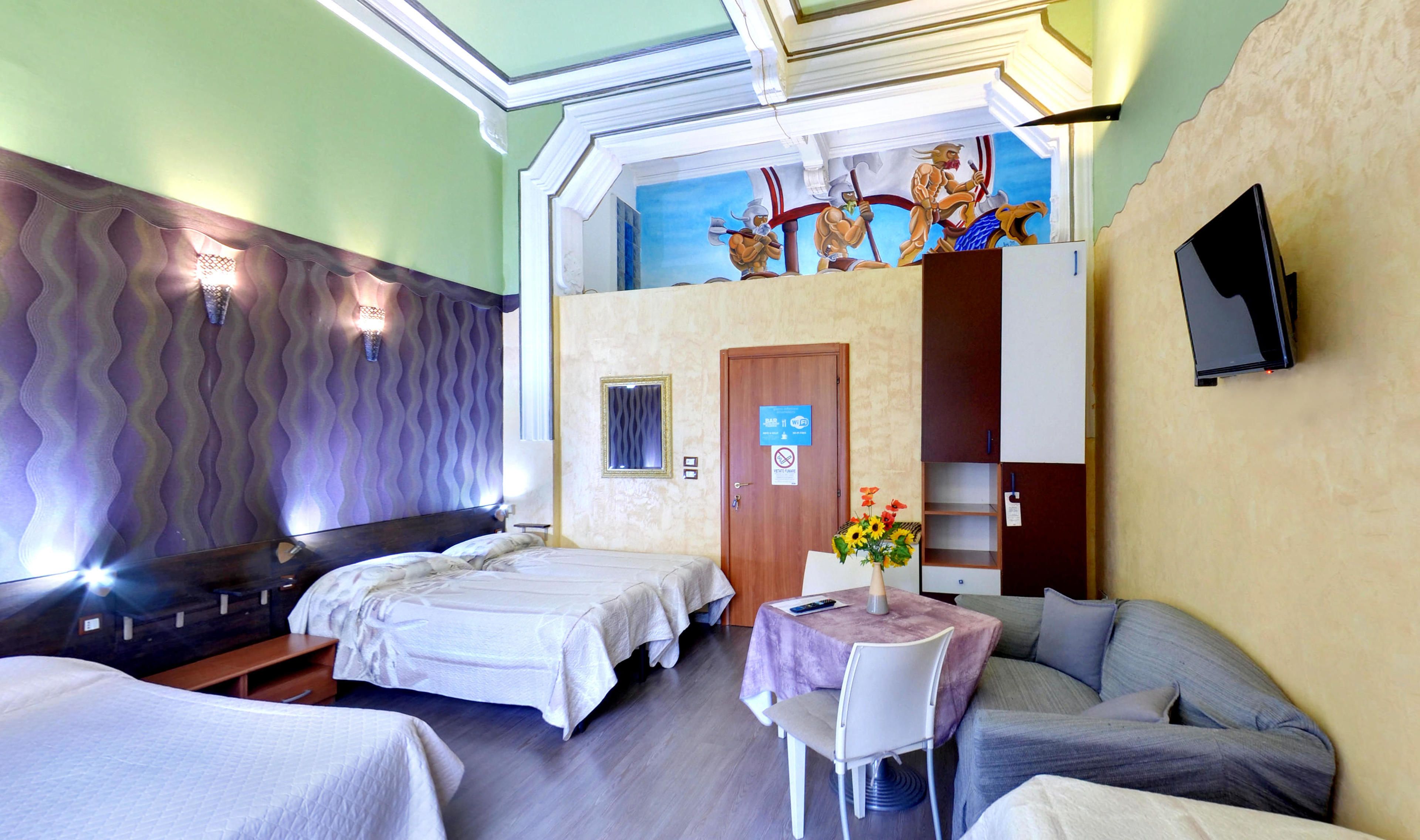 A hotel room with two beds, a small table with a vase of flowers, a sofa, a ceiling mural, and a TV mounted on the wall.