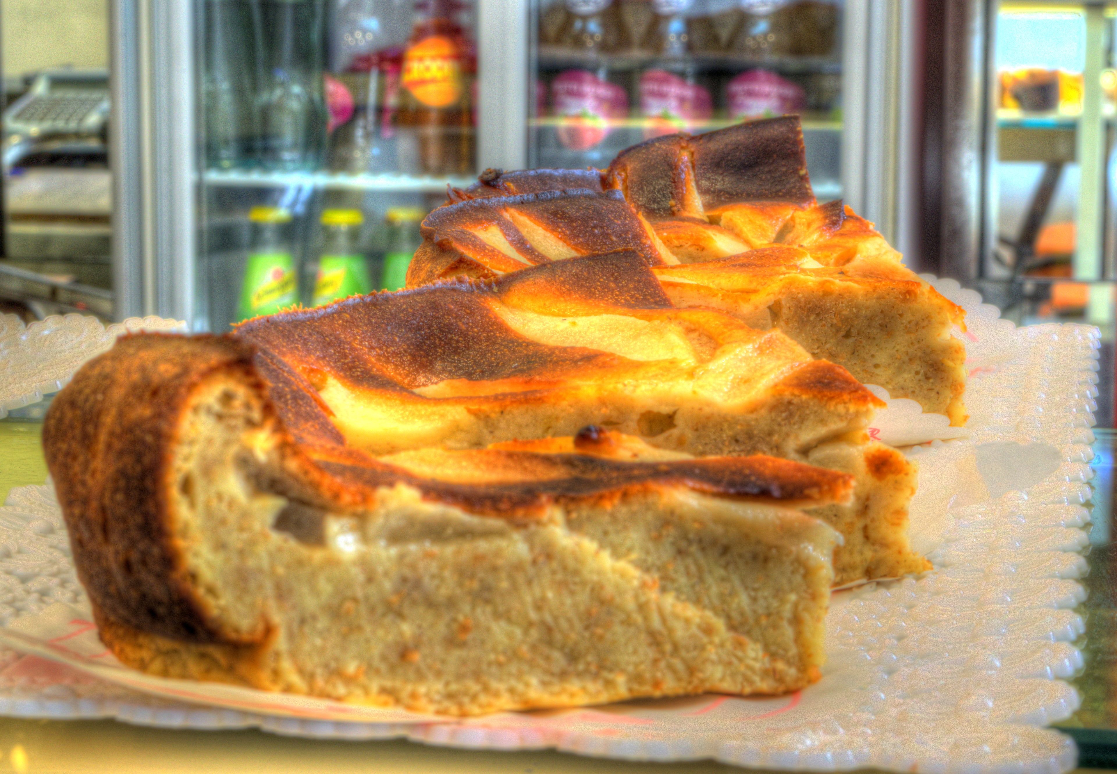 A slice of cake on a plate with a glass display case in the background.