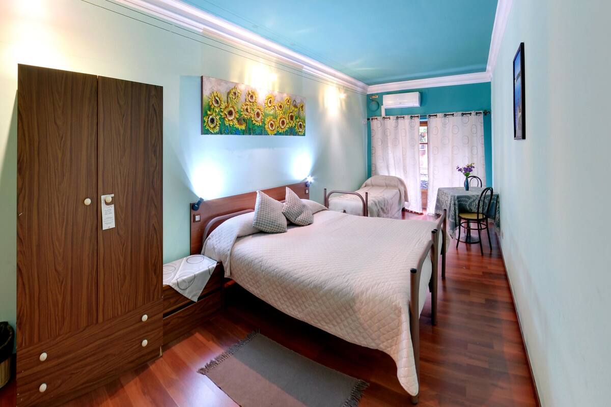 A bedroom with a bed, wooden wardrobe, and a painting on the wall.