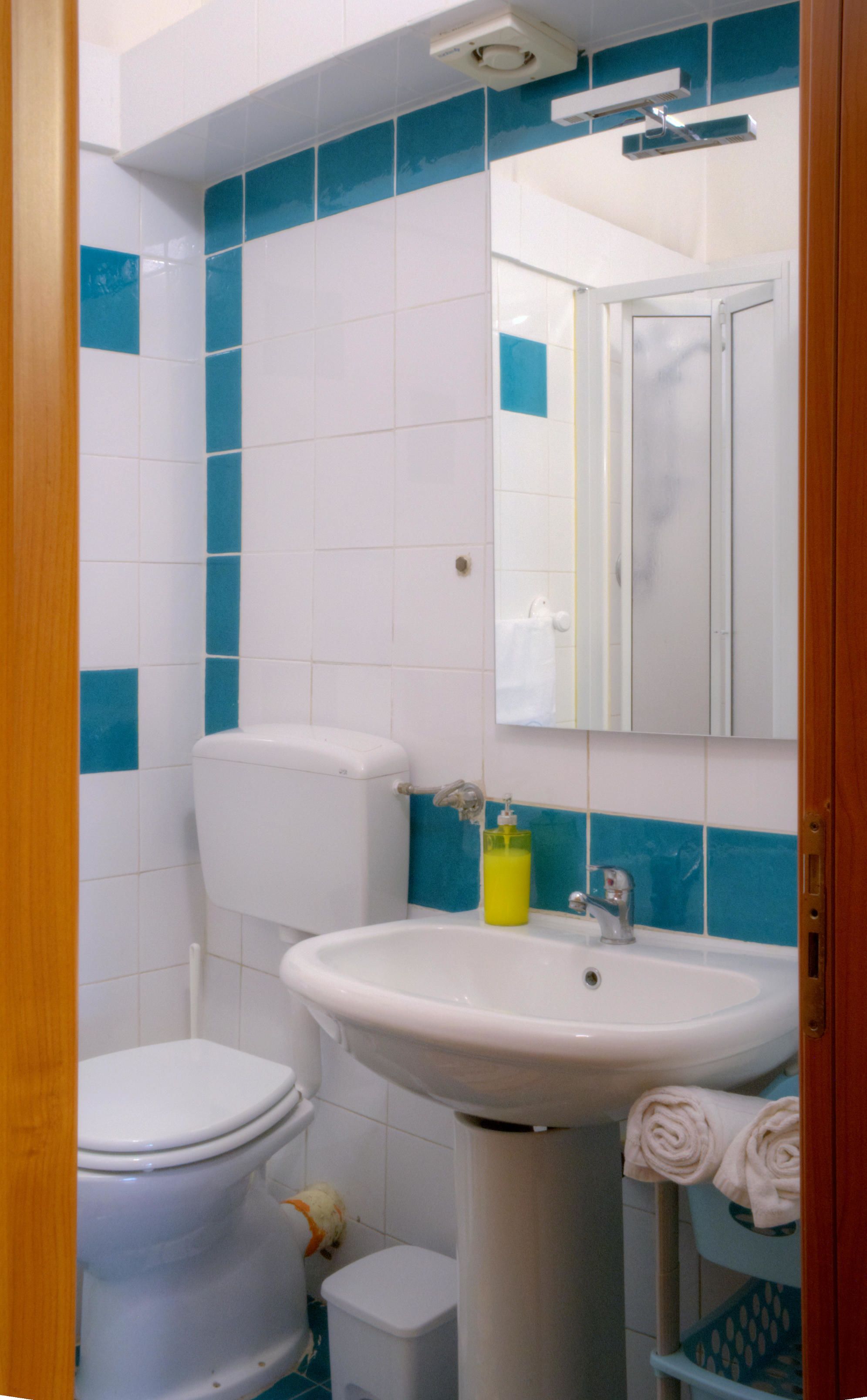 A bathroom with a toilet, sink, and mirror.