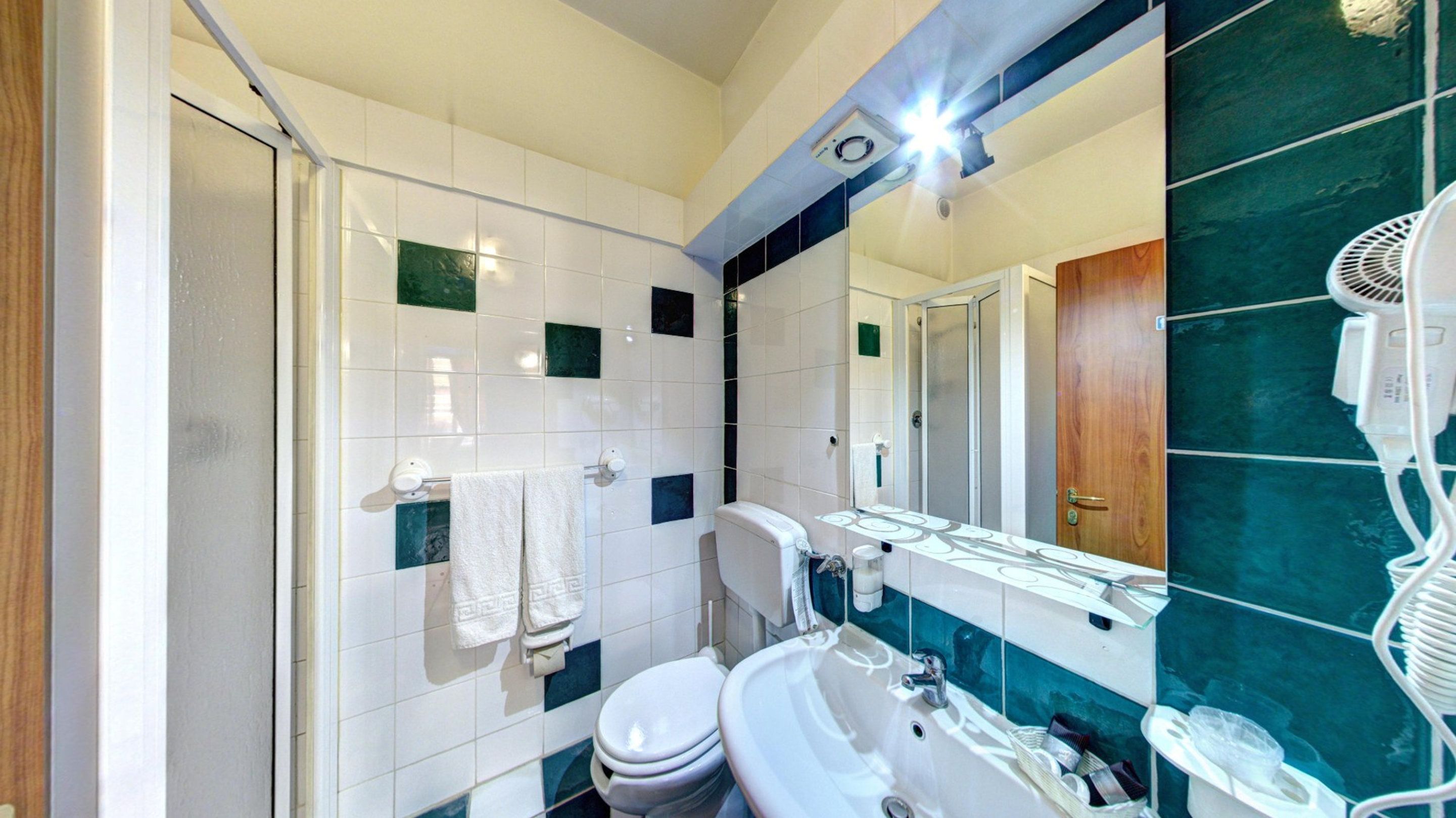 A bathroom with a shower, toilet, sink, and a mirror.