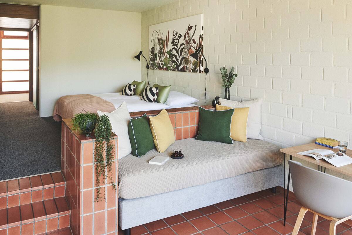 Una habitación acogedora con un sofá, una mesita y un separador de ladrillo.