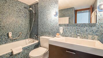 Une salle de bain avec un mur recouvert de mosaïques, une baignoire, des toilettes, un lavabo et un miroir.